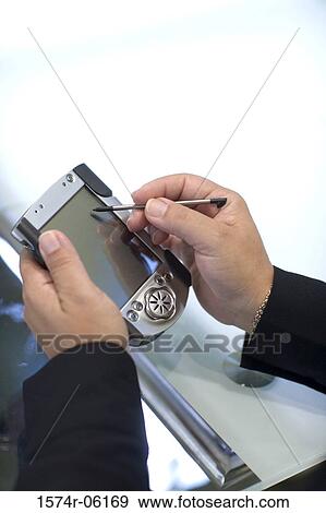 Stock Photo - Close-up of a person's hands using a hand held device. Fotosearch