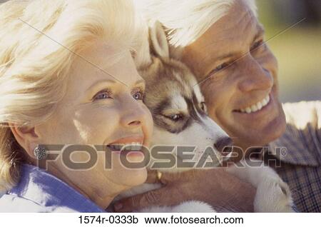 Stock Image - Close-up of a senior couple hugging their dog. Fotosearch