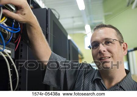 Stock Image - Close-up of a technician checking cables of a computer network. Fotosearch