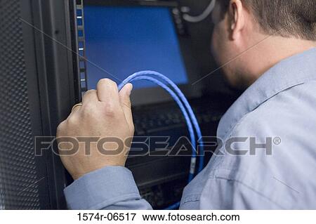 Stock Photo - Close-up of a technician looking at a computer monitor in a server room. Fotosearch