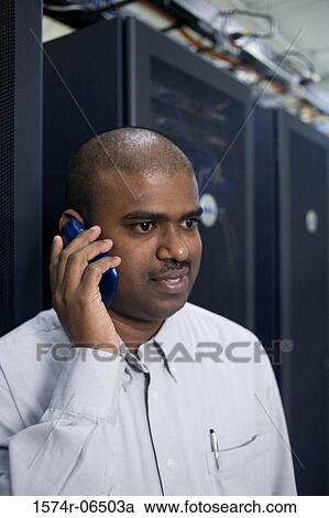 Stock Image - Close-up of a technician talking on a mobile phone. Fotosearch
