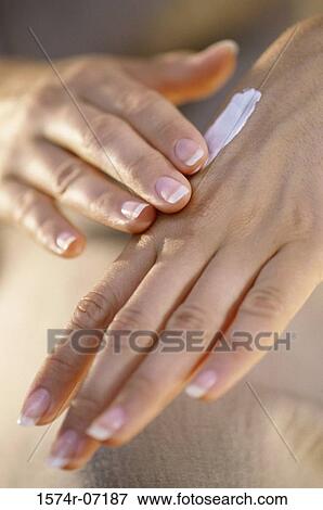 Stock Photo - Close-up of a woman applying cream on her hands. Fotosearch