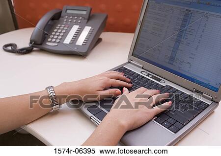 Stock Photography - Close-up of a woman's hands working on a laptop in an office. Fotosearch