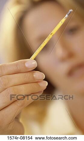 Close-up of a young woman holding a thermometer View Large Photo Image Picture - Close-up of a young woman holding a thermometer. Fotosearch