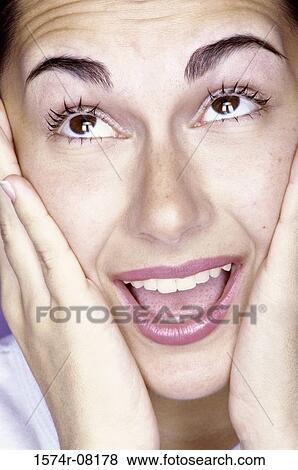 Close-up of a young woman with her hands on her face View Large Photo Image Stock Photo - Close-up of a young woman with her hands on her face. Fotosearch