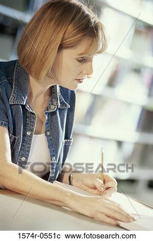 Close-up of a young woman writing in a notebook View Large Photo Image Stock Image - Close-up of a young woman writing in a notebook. Fotosearch