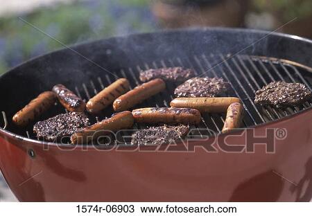 Stock Image - Close-up of hamburgers and hot dogs cooking on a barbecue grill. Fotosearch