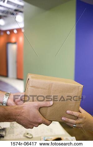Stock Photo - Close-up of the hands of two people holding a box. Fotosearch