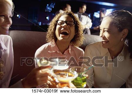 Stock Image - Close-up of three young women toasting with glasses. Fotosearch