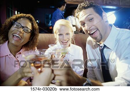 Close-up of two young women and young man toasting with glasses View Large Photo Image Stock Image - Close-up of two young women and young man toasting with glasses. Fotosearch