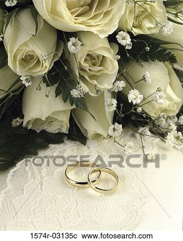 Stock Image - Close-up of wedding rings with a bouquet of flowers. Fotosearch