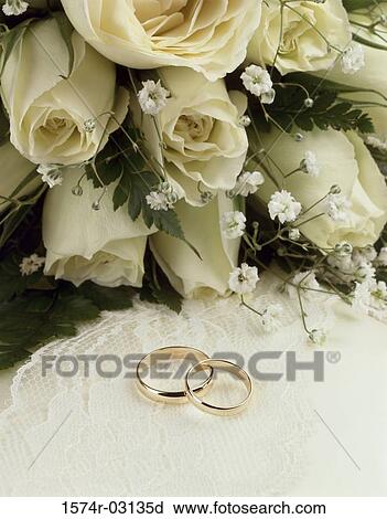 Stock Image - Close-up of wedding rings with a bouquet of flowers. Fotosearch