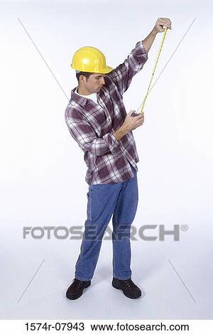 Stock Image - Construction worker holding a measuring tape. Fotosearch