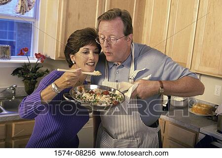 Couple cooking together in a kitchen View Large Photo Image Stock Photograph - Couple cooking together in a kitchen. Fotosearch