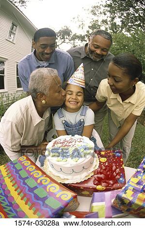 Stock Image - Daughter celebrating her birthday with her parents and grandparents. Fotosearch