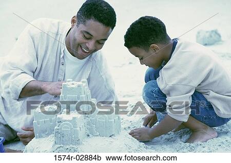 Stock Image - Father and his son making sand castles on the beach. Fotosearch