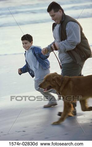 Father and his son running with their dog on the beach View Large Photo Image Stock Image - Father and his son running with their dog on the beach. Fotosearch