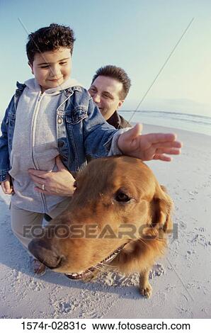 Stock Image - Father and his son with their dog on the beach. Fotosearch