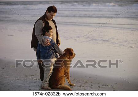 Stock Image - Father and his son with their dog on the beach. Fotosearch