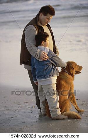 Stock Image - Father and his son with their dog on the beach. Fotosearch