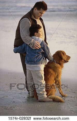 Stock Image - Father and his son with their dog on the beach. Fotosearch