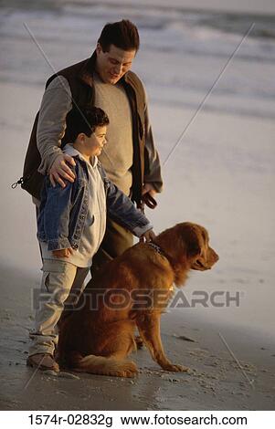 Stock Image - Father and his son with their dog on the beach. Fotosearch