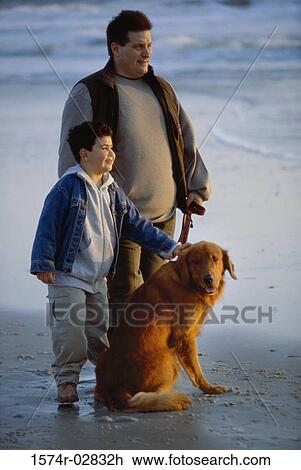 Stock Image - Father and his son with their dog on the beach. Fotosearch