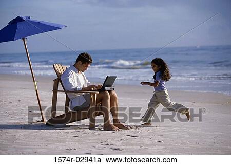 Father working on a laptop with his daughter running on the beach View Large Photo Image Stock Image - Father working on a laptop with his daughter running on the beach. Fotosearch