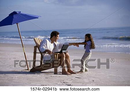Stock Image - Father working on a laptop with his daughter pulling at his arm. Fotosearch