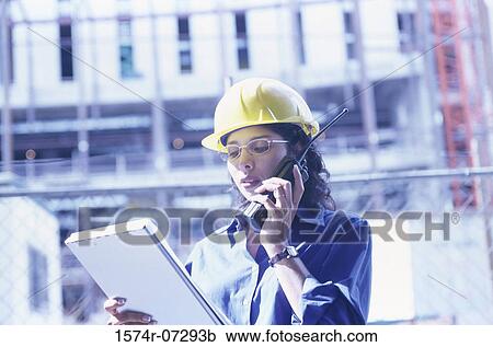 Stock Image - Forewoman talking on a walkie-talkie. Fotosearch