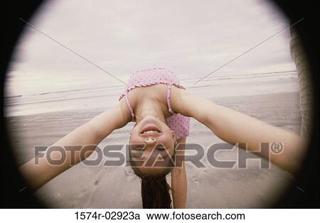 Stock Image - Girl bending over backwards on the beach. Fotosearch
