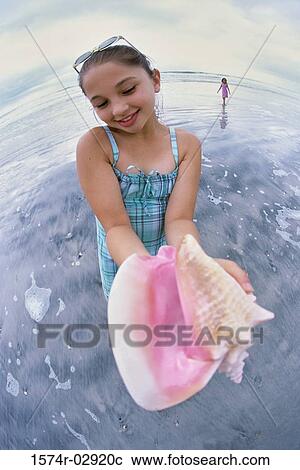 Girl holding a conch shell View Large Photo Image Stock Image - Girl holding a conch shell. Fotosearch