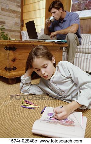 Girl lying on the floor with her father working on a laptop behind her View Large Photo Image Stock Image - Girl lying on the floor with her father working on a laptop behind her. Fotosearch