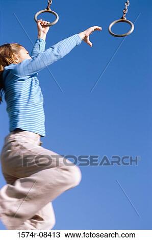 Stock Image - Girl playing on monkey bars at a playground. Fotosearch
