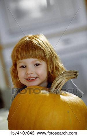 Girl smiling next to a pumpkin View Large Photo Image Stock Image - Girl smiling next to a pumpkin. Fotosearch