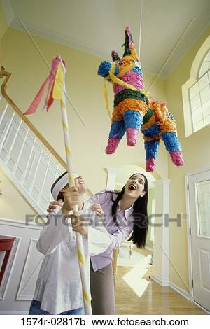 Stock Image - Girl wearing a blindfold hitting a pinata with a stick. Fotosearch