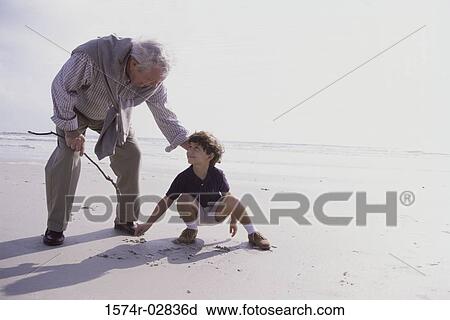 Stock Image - Grandfather playing with his grandson on the beach. Fotosearch