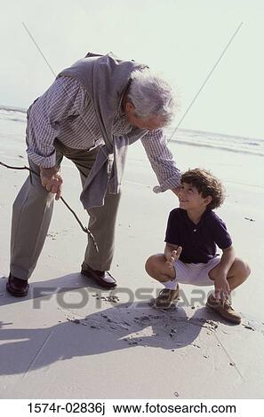 Stock Image - Grandfather playing with his grandson on the beach. Fotosearch
