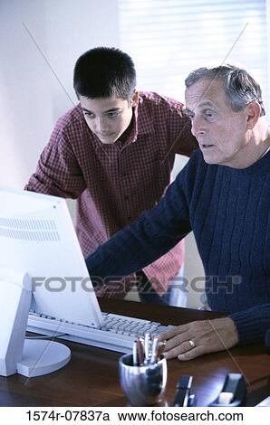 Stock Image - Grandfather working on a computer with his grandson. Fotosearch