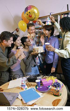 Stock Image - Group of business executives celebrating a birthday in the office. Fotosearch