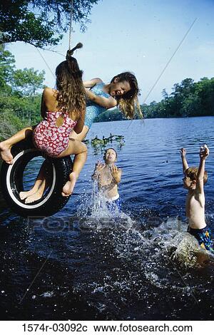 Stock Image - Group of children playing on a tire swing. Fotosearch