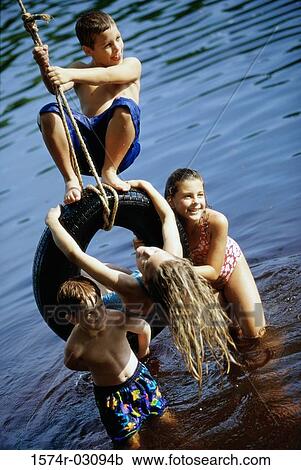 Group of children playing on a tire swing View Large Photo Image Stock Image - Group of children playing on a tire swing. Fotosearch