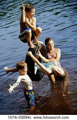 Group of children playing on a tire swing View Large Photo Image Stock Image - Group of children playing on a tire swing. Fotosearch