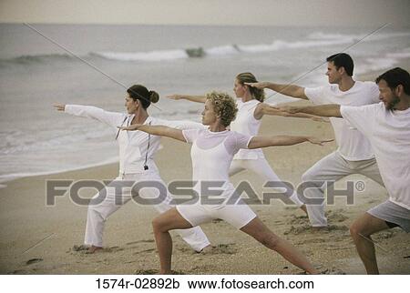 Stock Image - Group of people exercising on the beach. Fotosearch