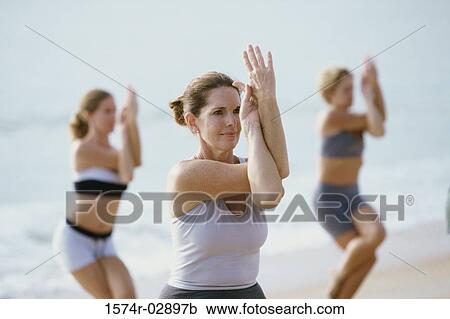 Group of people performing yoga on the beach View Large Photo Image Stock Image - Group of people performing yoga on the beach. Fotosearch