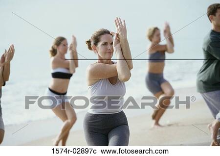 Group of people performing yoga on the beach View Large Photo Image Stock Image - Group of people performing yoga on the beach. Fotosearch