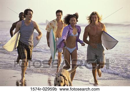 Stock Image - Group of young people running on the beach. Fotosearch