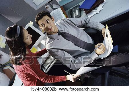 Stock Image - High angle view of a businessman and a businesswoman discussing a report. Fotosearch