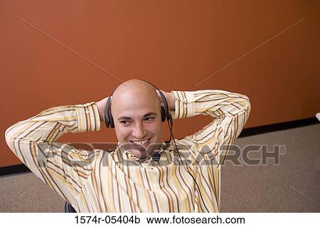 Stock Image - High angle view of a businessman wearing a headset in an office. Fotosearch