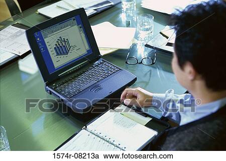 Stock Image - High angle view of a businessman sitting in front of a laptop. Fotosearch